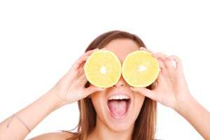 Woman holding orange slices over eyes