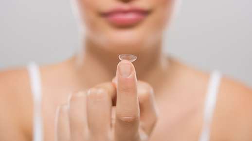 Fingertip balancing a contact lens 