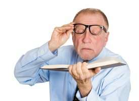 Older man trying to read book closely 