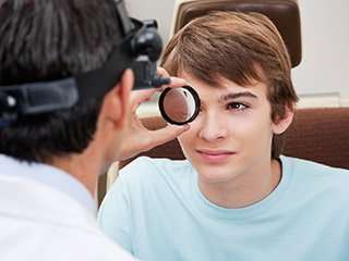 Eye Doctor looking at teenage boy's eye 