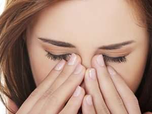 Woman pressing fingers into the corners of her eyes